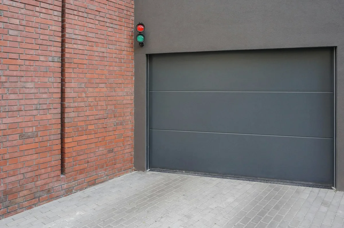 Grey steel garage door set into a brick wall